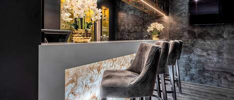 A reception area with a marble counter, plush chairs, and a wall-mounted TV.