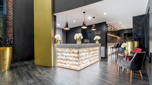 Zona de bar moderna con mostrador central, iluminación colgante y asientos.