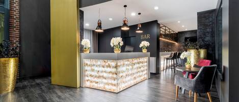 A modern bar area with a central counter, overhead lighting, and seating.