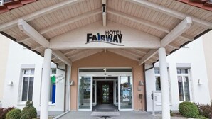 La entrada del Hotel Fairway, con un porche cubierto, escalones que conducen a la puerta y un cartel sobre la entrada.