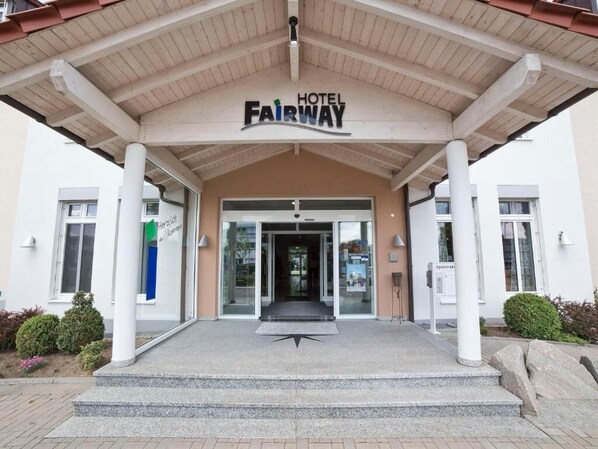 The entrance to Hotel Fairway with a covered entrance, steps leading up to the door, and a sign above the entrance. - Fairway Hotel (Sankt Leon-Rot)