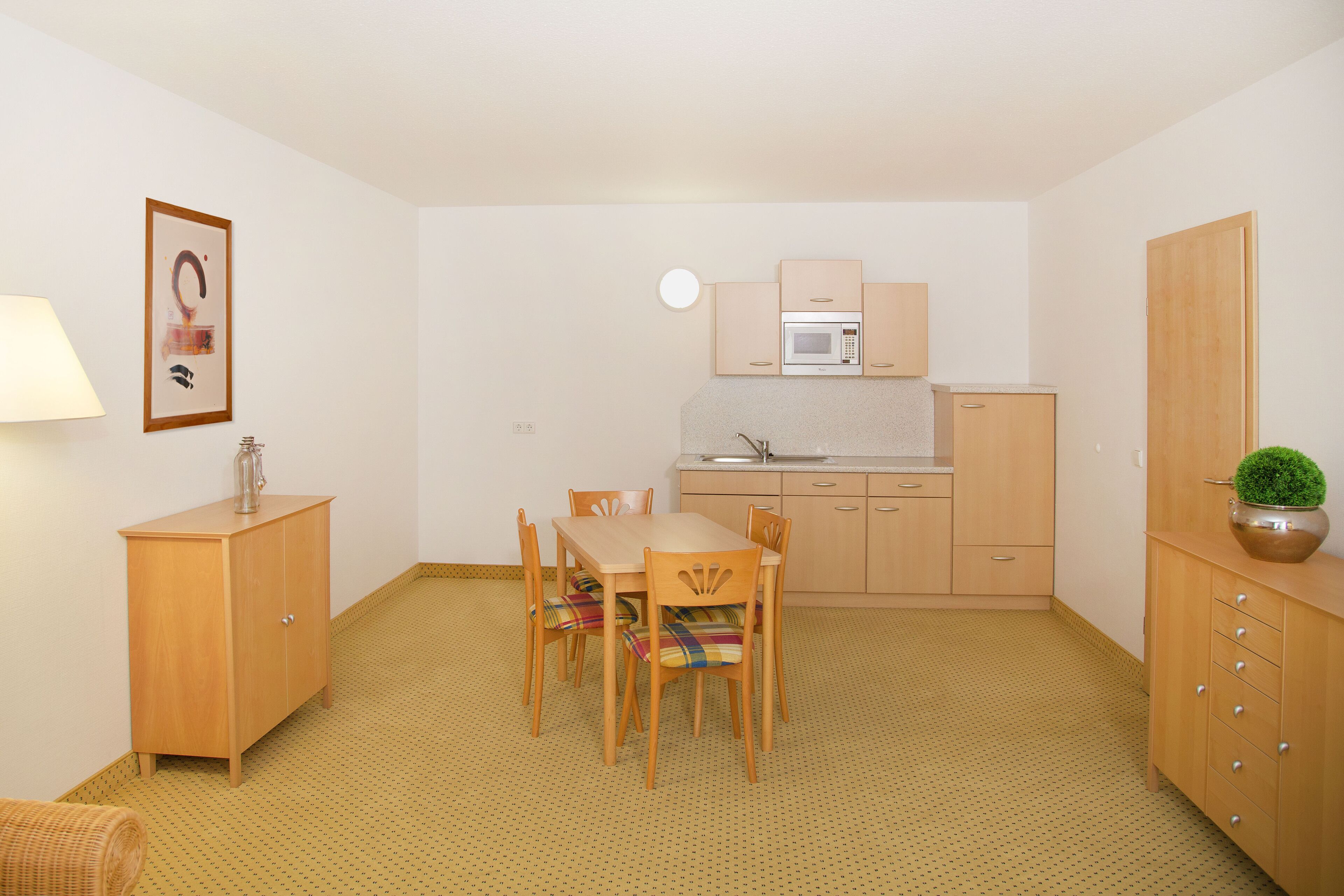 Una cocina compacta con una mesa y sillas, un microondas y un lavamanos.