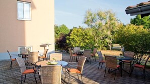 Un patio exterior con mobiliario de mimbre y suelo de baldosas.