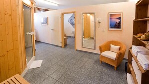 Habitación de hotel con un armario de madera, una silla de mimbre, un espejo y un cuadro en la pared.