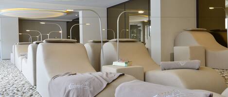 A modern hotel room with a massage area featuring reclining chairs and a massage table.