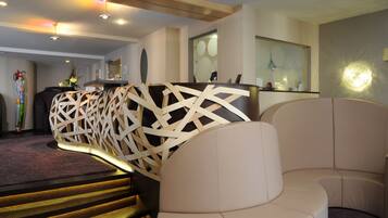 Un interior moderno con una escalera, un mostrador de recepción y una zona de estar.