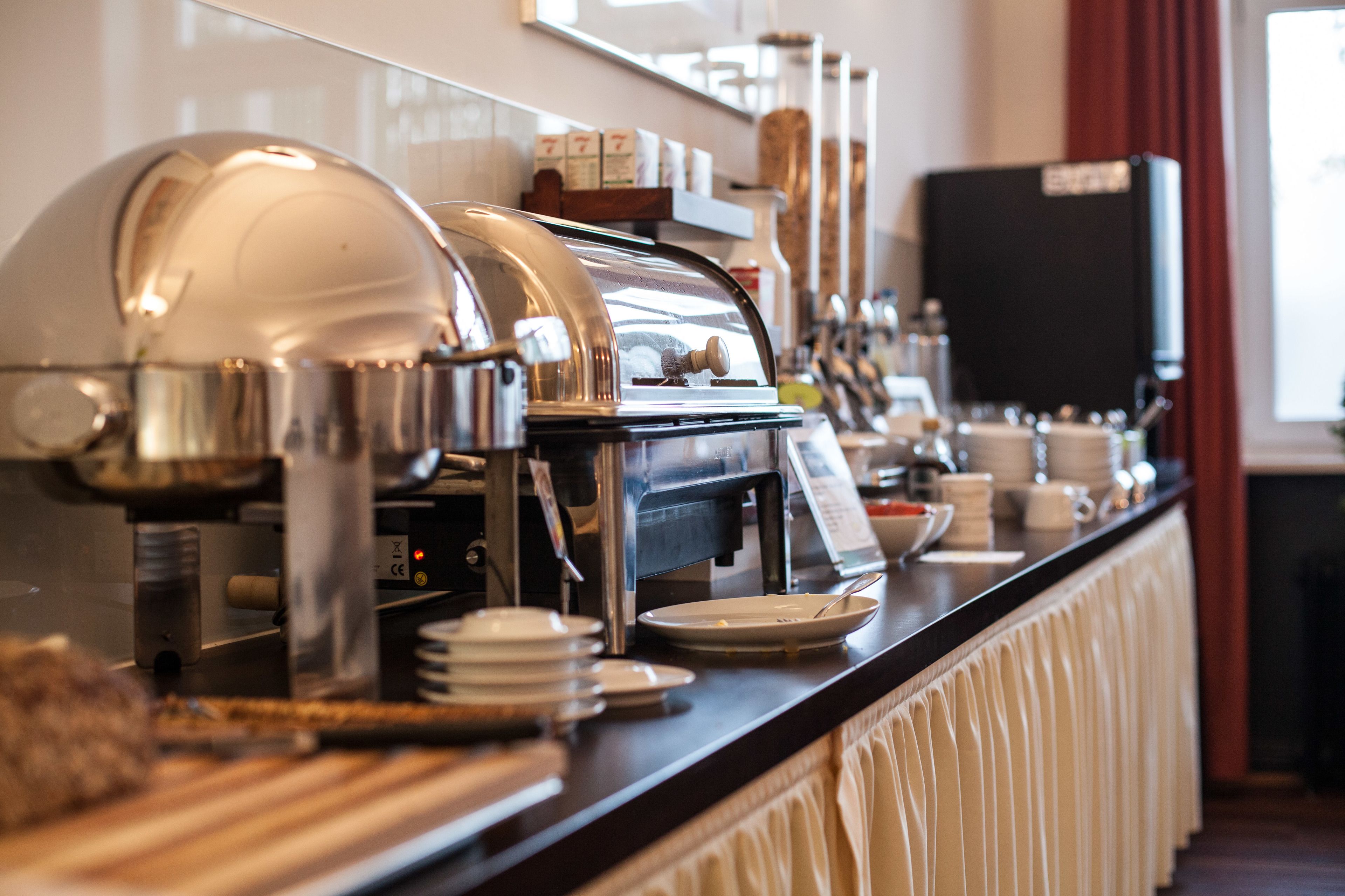 A buffet setup with various food containers and a coffee machine.