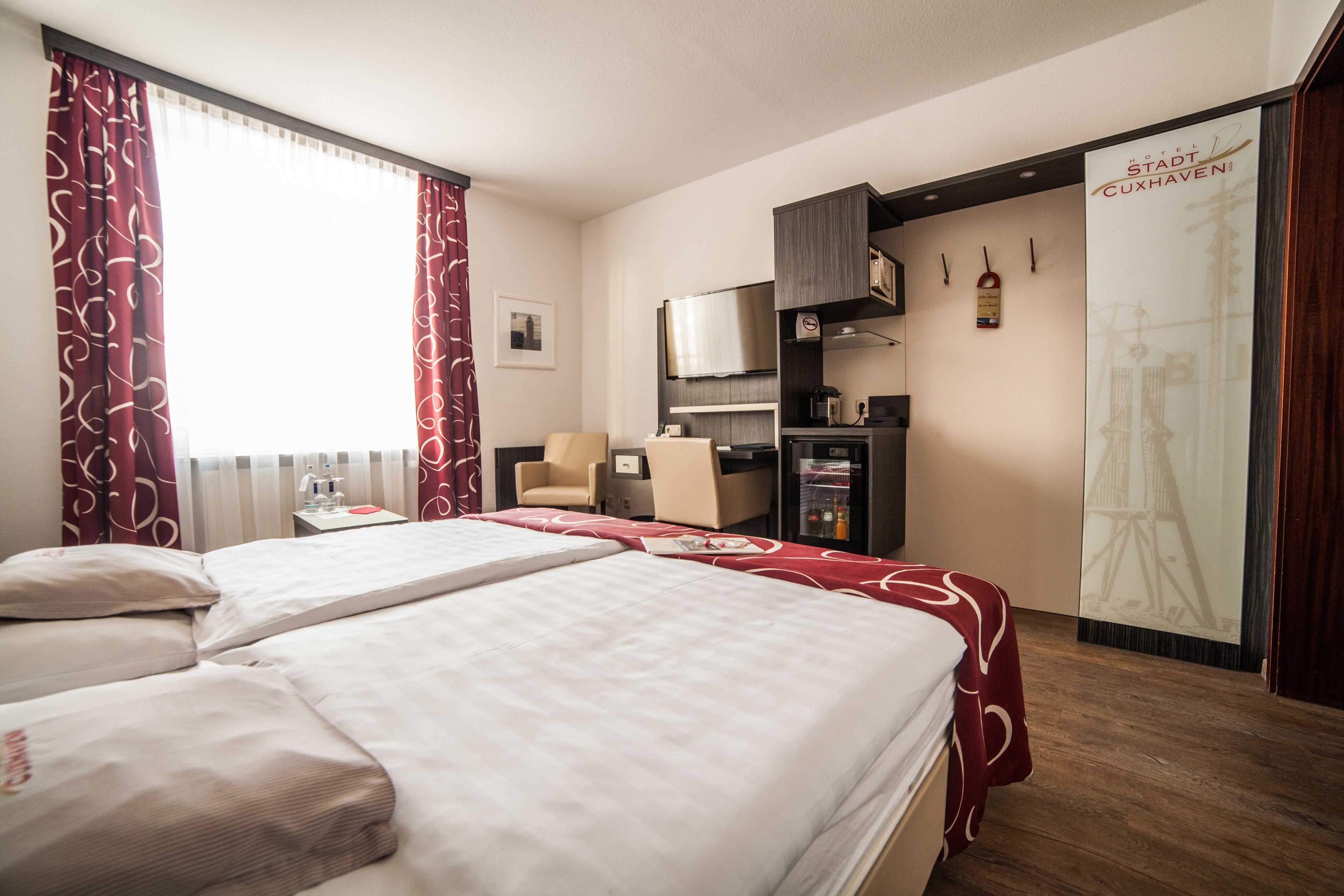 Habitación de hotel con dos camas, televisión, minibar y vistas a la Torre Eiffel.