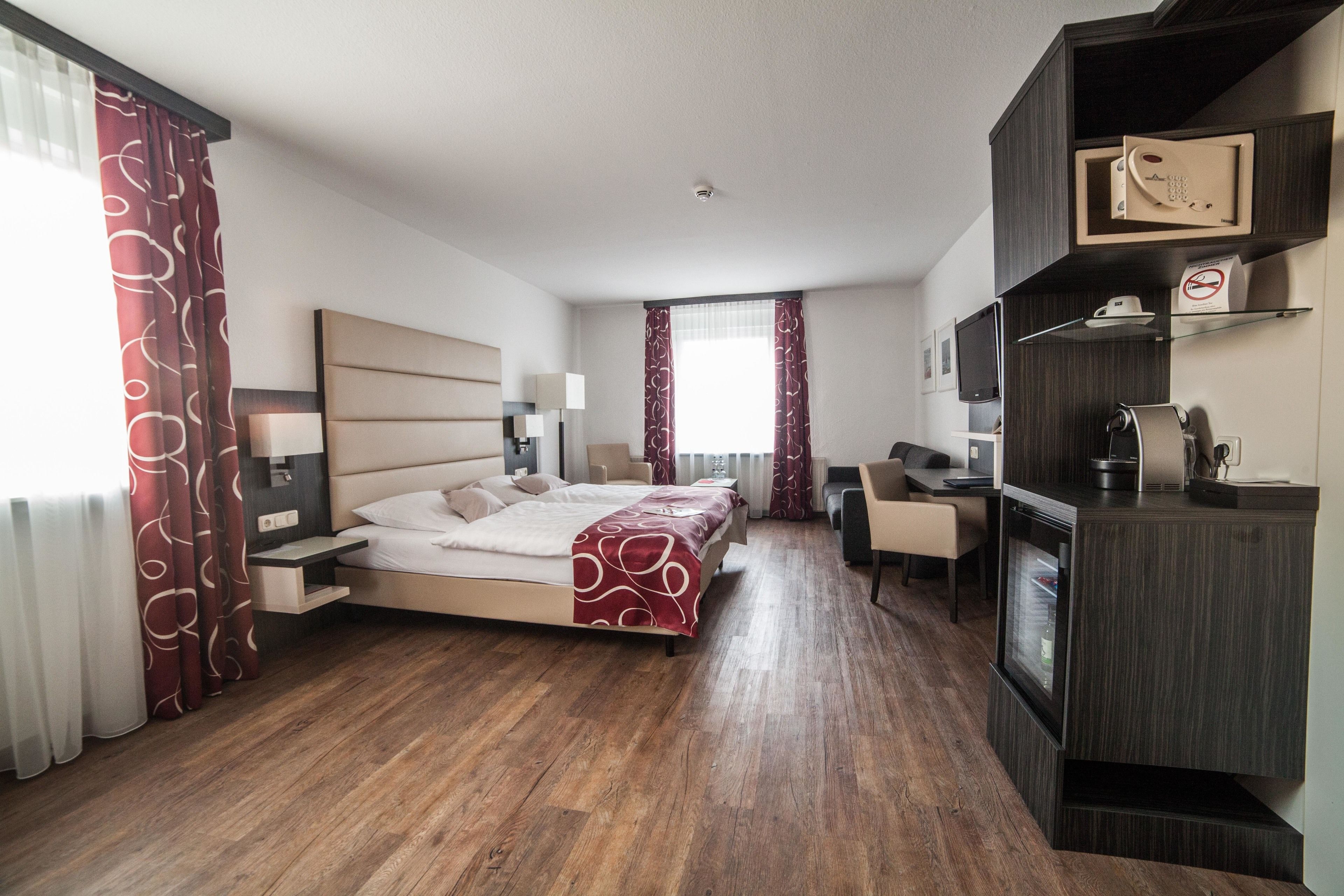 Een moderne hotelkamer met een groot bed, een bureau en een kitchenette.