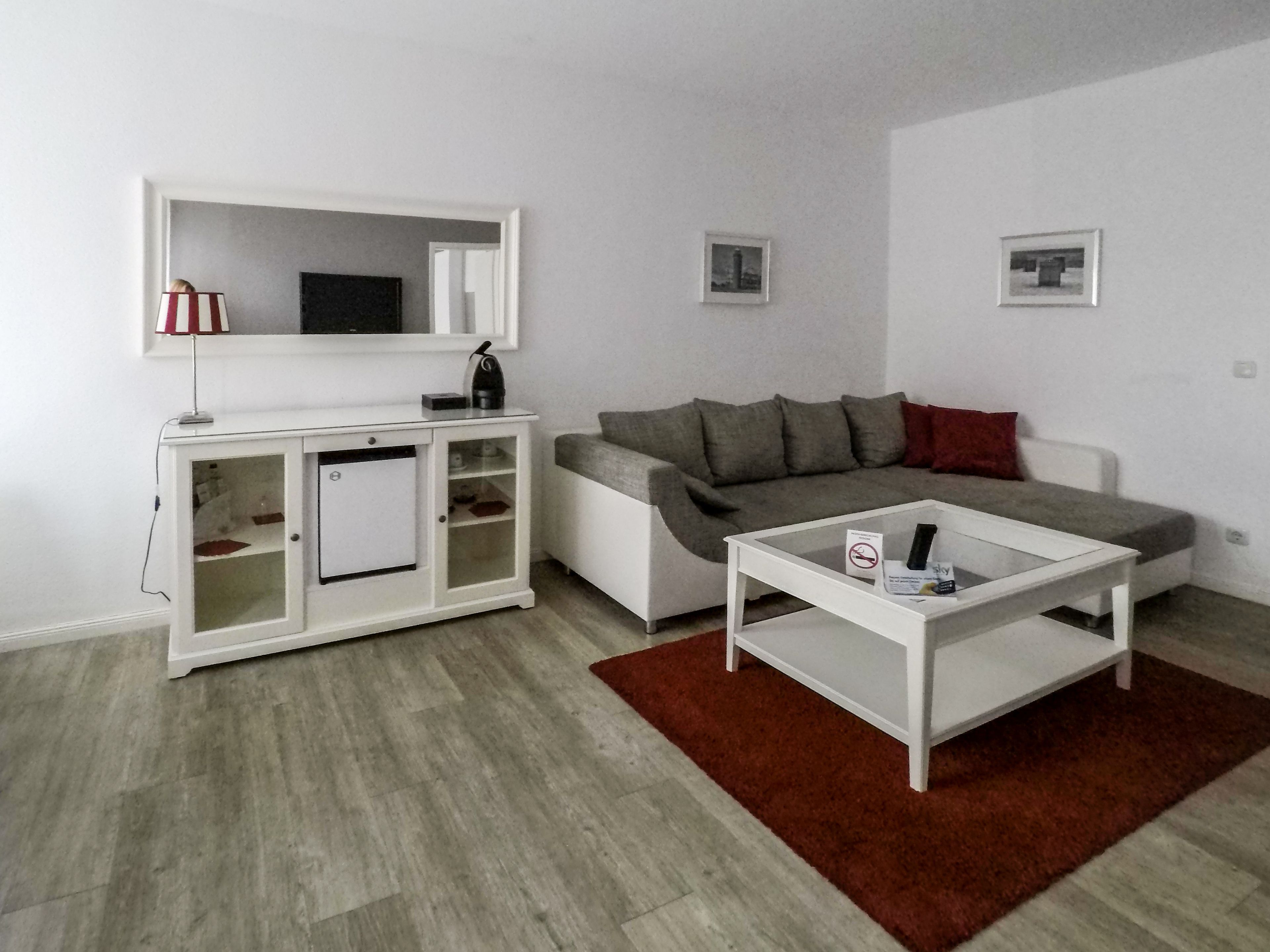 Una sala de estar moderna con un sofá blanco, un mueble blanco pequeño y una mesa de centro.