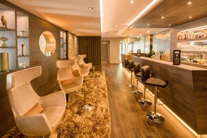 A modern bar area with bar stools and a counter displaying bottles.