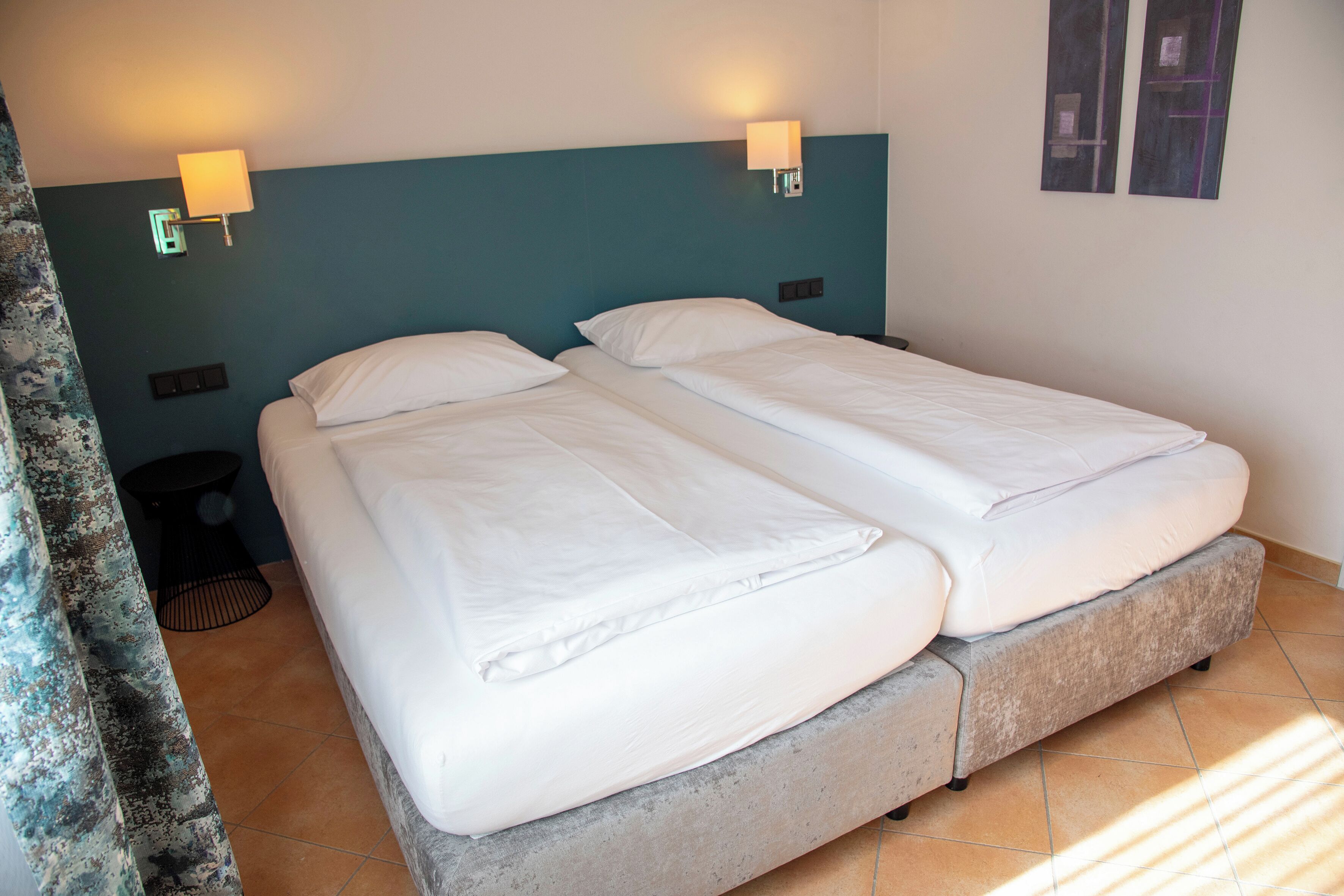 Un lit double avec une tête de lit en béton dans une chambre d’hôtel.