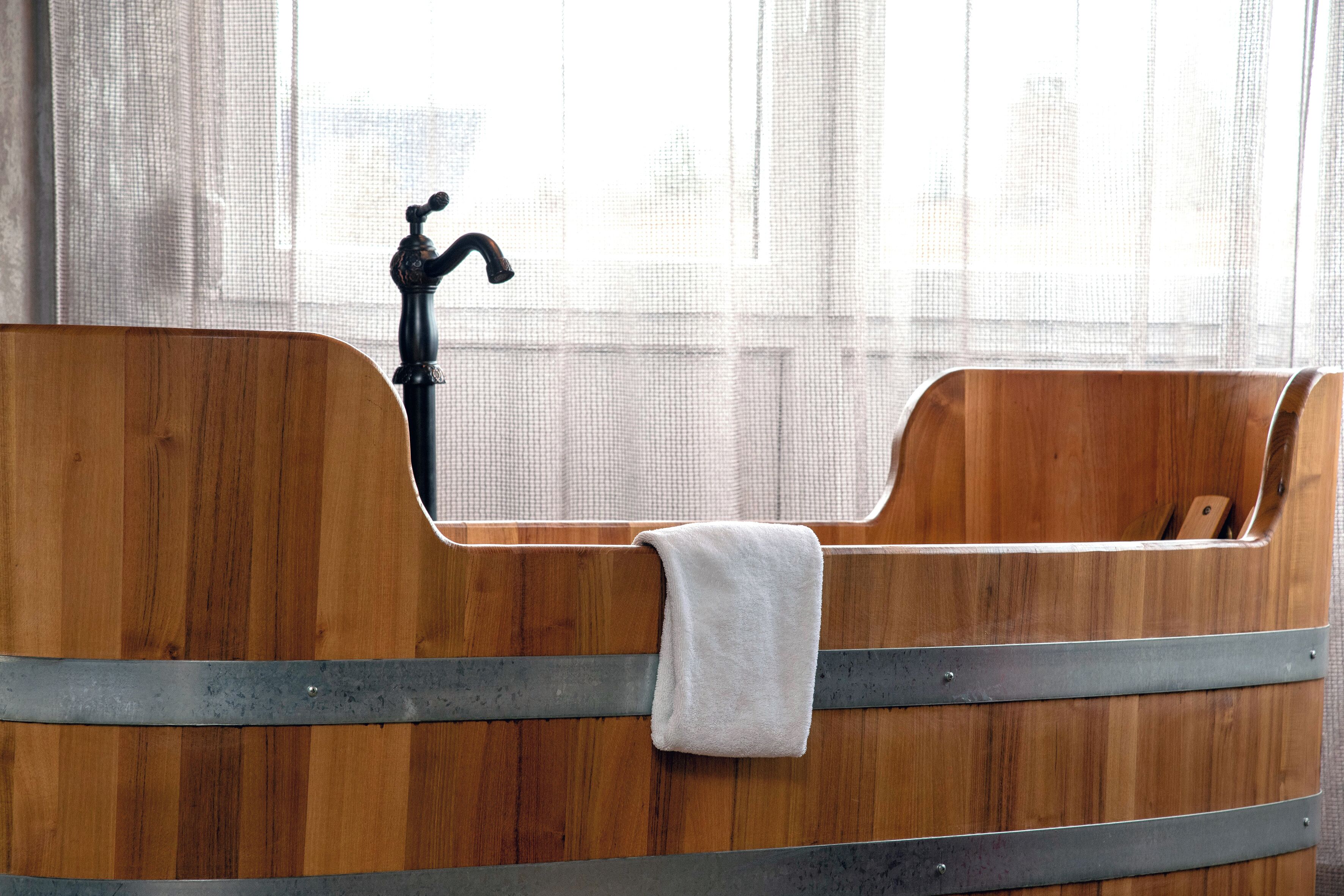 A wooden bathtub with a faucet and a towel.