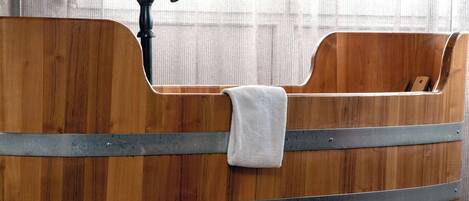A wooden bathtub with a faucet and a towel.