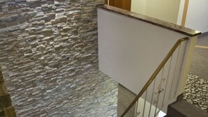 Una escalera con un muro de piedra a un lado y un suelo de madera al otro.