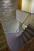 A staircase with a stone wall on one side and a wooden floor on the other.