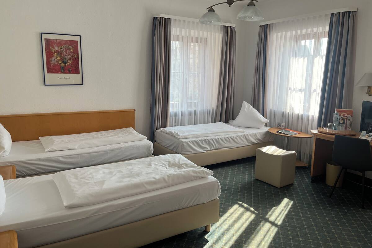 A hotel room with two beds, a desk, and a chair.