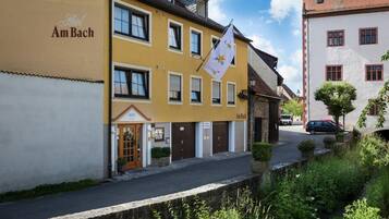 A yellow building with the sign "Hotel Am Bach" and a flag with a star and the word "SICH".