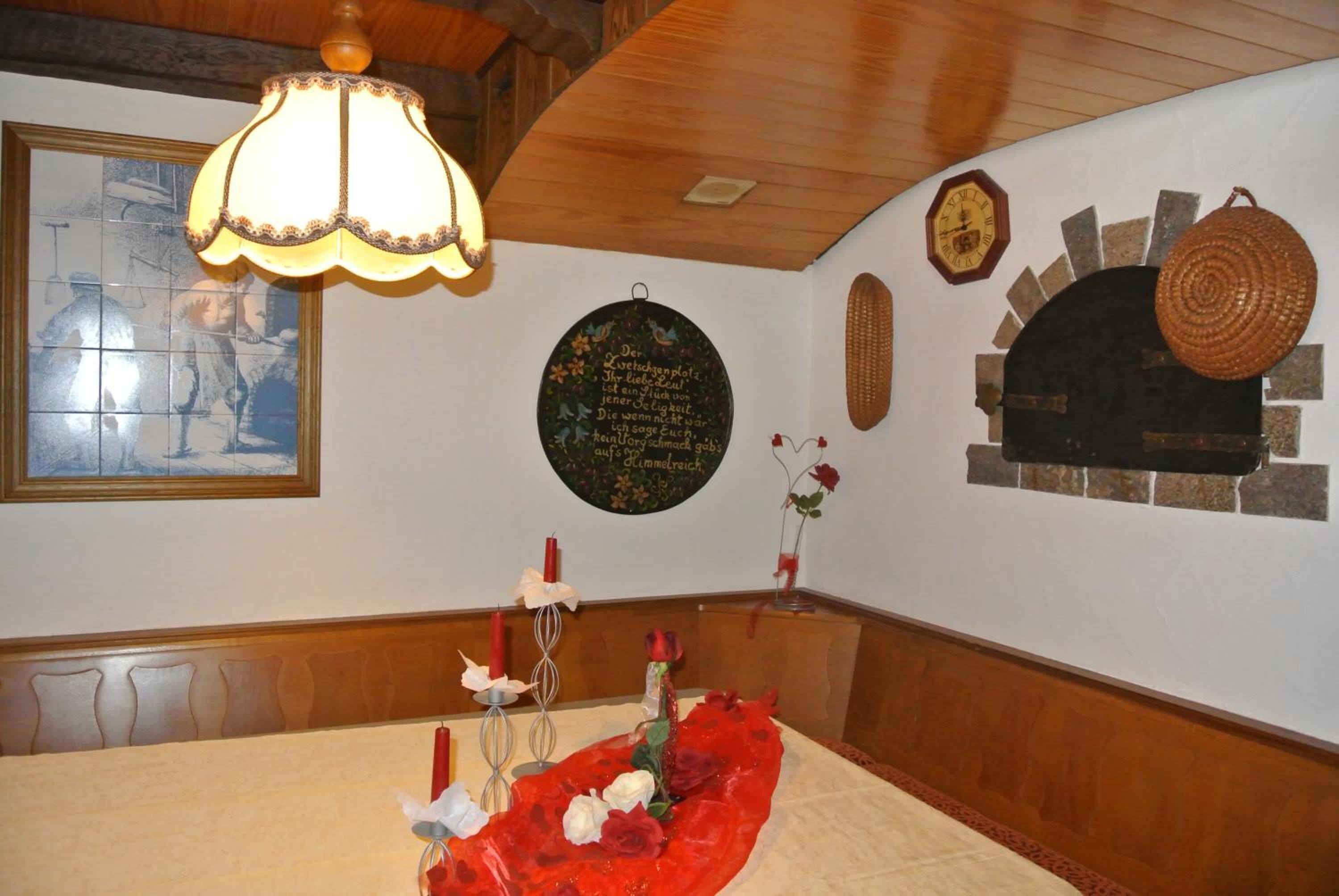 Un comedor con techo de madera, un candelabro, un reloj en la pared y una chimenea rústica.