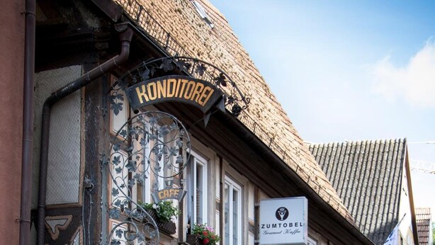 Un edificio tradicional europeo con un letrero que indica 'Konditorei' y restaurante 'Zumtobel'.