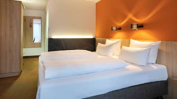 Una habitación de hotel con una cama grande, un armario y dos lámparas fijadas a la pared.