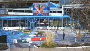 A modern building with a swimming pool, glass windows, and a distinctive logo. - Mercure Hotel Stuttgart Zuffenhausen (Stuttgart)