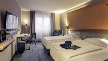 A hotel room with two beds, a desk with a chair, a television, and a window with curtains.
