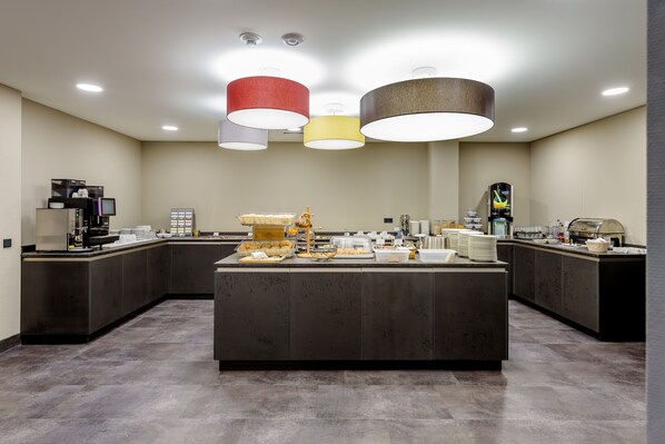 A modern kitchen with a central island, equipped with various appliances and food items. - Mercure Hotel Stuttgart Zuffenhausen (Stuttgart)