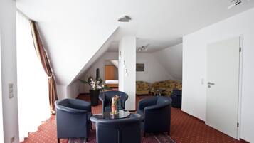 Una sala de estar moderna con techo alto, una escalera y vista a un dormitorio.