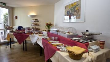A buffet setup with various food items and a painting on the wall.