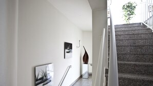 A staircase with a handrail, a wall-mounted picture, and a plant. - Hotel Am Braunen Hirsch (Celle)