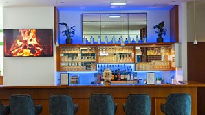 A bar area with a long counter, multiple shelves of glassware and bottles, and a fire painting on the wall. - ACRON Hotel Quedlinburg (Quedlinburg)