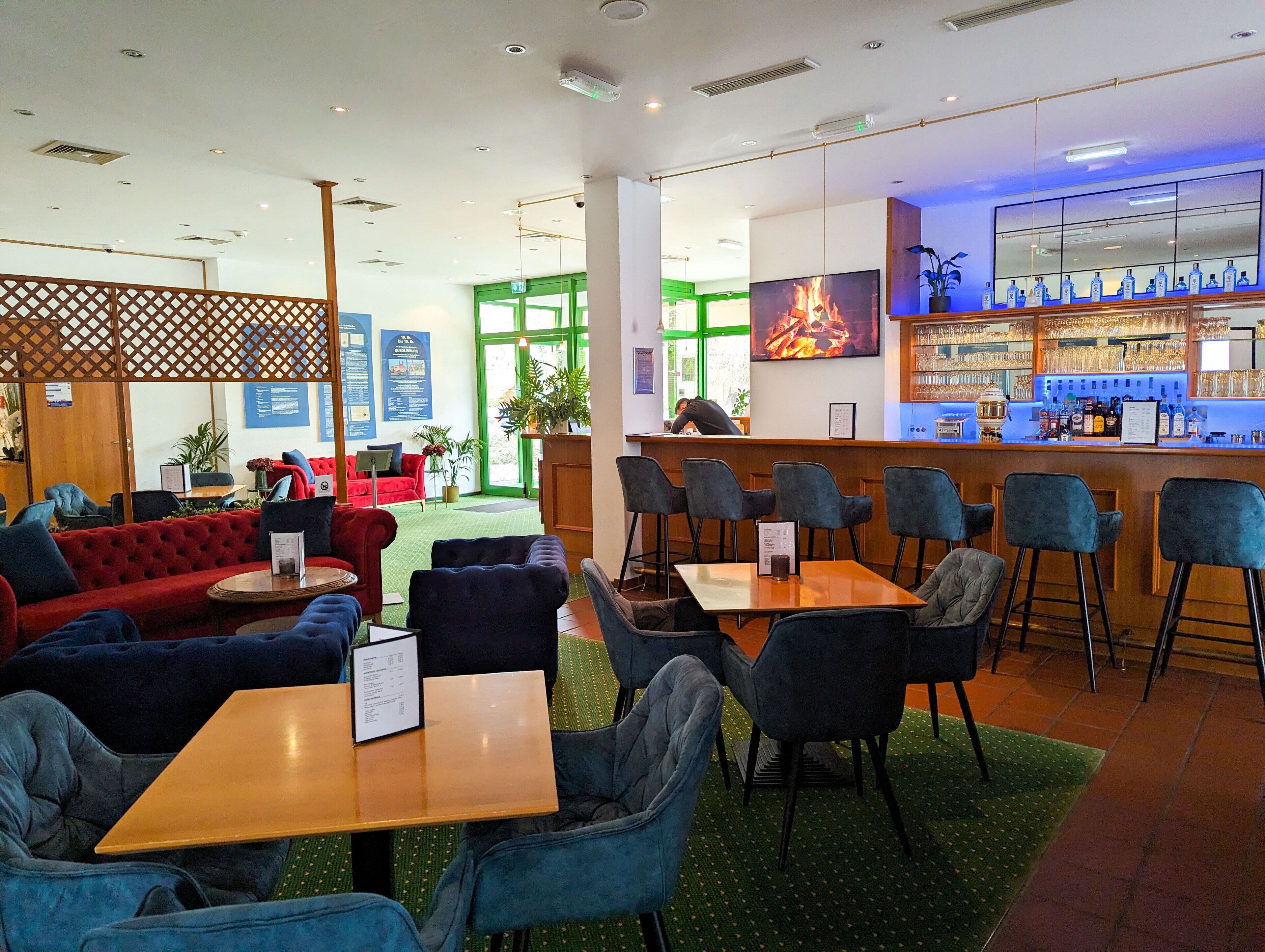 A modern bar area with seating and a television displaying a fire.