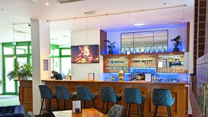 A bar area with a counter, bar stools, and a seating area with tables and chairs. - ACRON Hotel Quedlinburg (Quedlinburg)