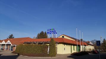 Ein Hotel namens "Acron Hotel" mit rotem Ziegeldach, einem Parkschild und einem gepflasterten Eingangsbereich.