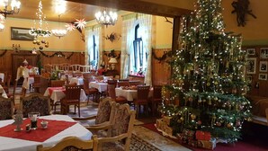 A warmly decorated dining area with a large Christmas tree, wooden furniture, and festive decorations. - Hotel Zum Bürgergarten (Südharz)