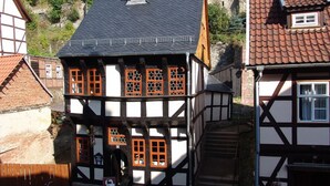 A traditional half-timbered house with a steeply pitched roof, multiple windows with wooden frames, and a visible staircase leading to the upper floor. - Hotel Zum Bürgergarten (Südharz)