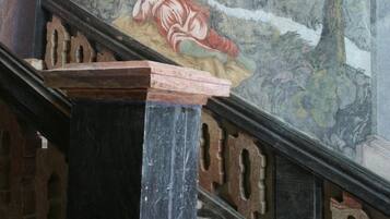 A staircase with a marble handrail and a mural depicting a landscape with trees and a figure.