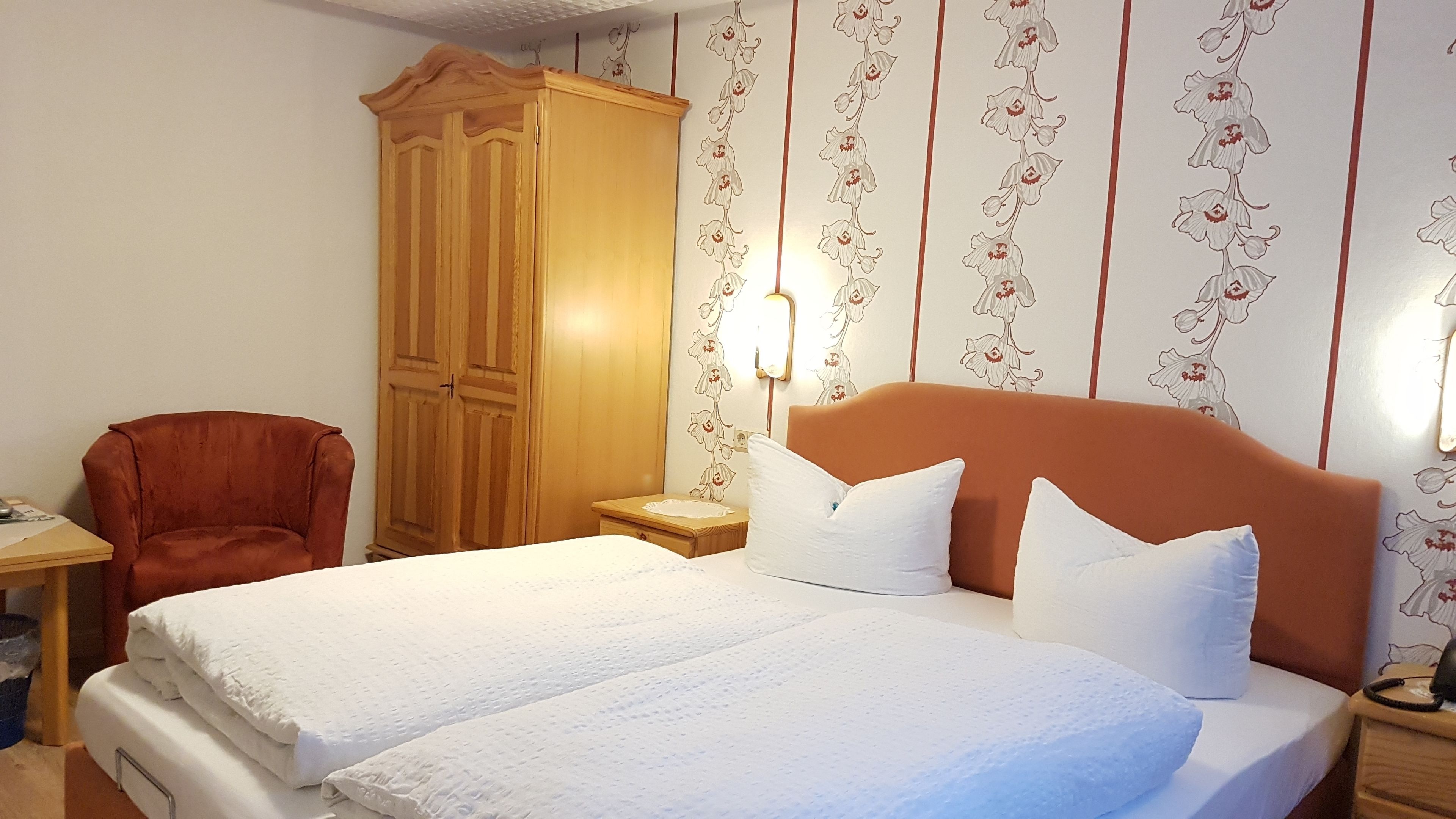 Ein Hotelzimmer mit einem großen Bett, einem Holzschrank, einem Schreibtisch und einem Stuhl.