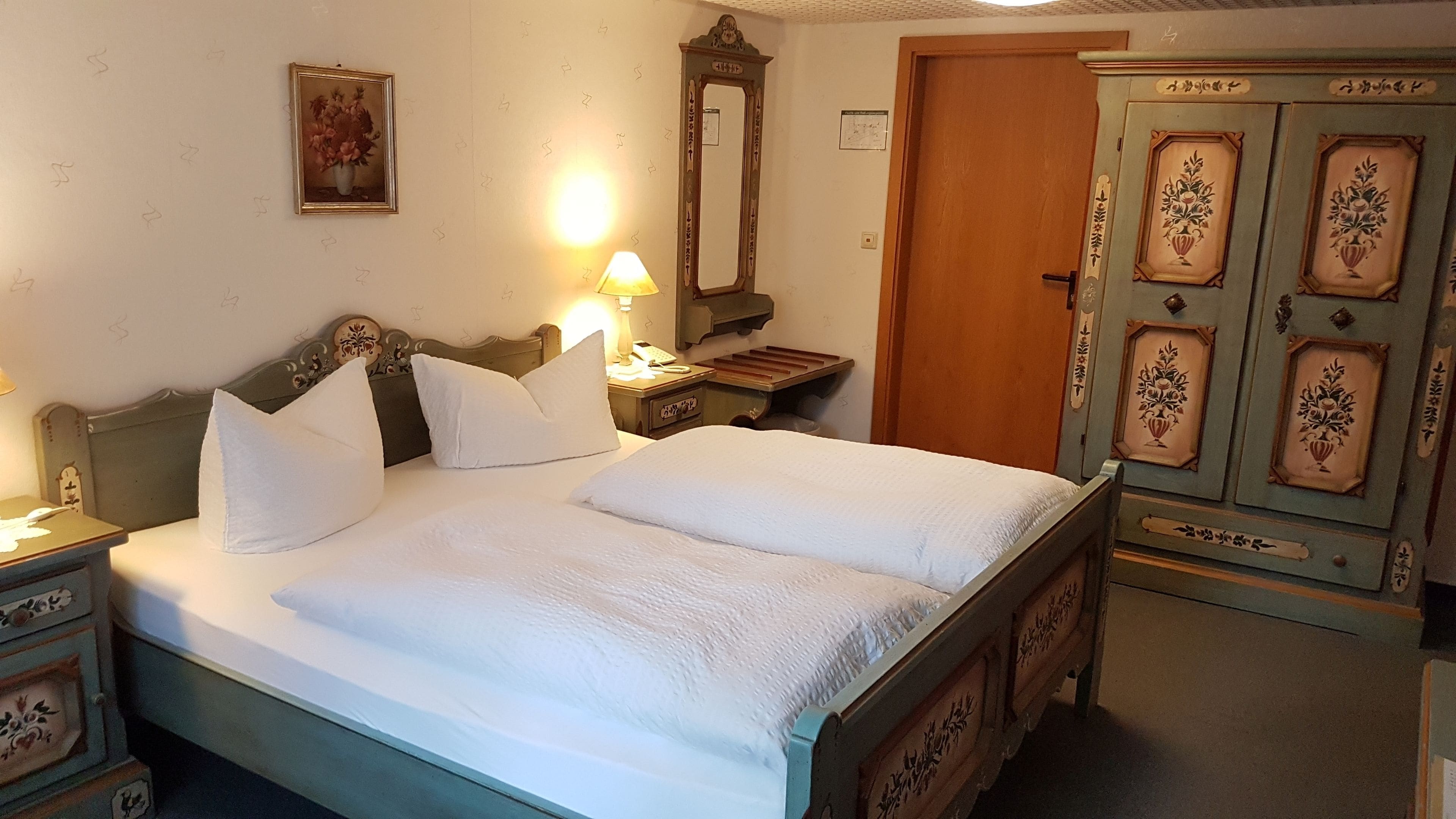 A bedroom with a bed, bedside tables, a lamp, a mirror, and a wardrobe.