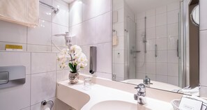 Een moderne badkamer met een grote spiegel, een wastafel en een douchehoek.