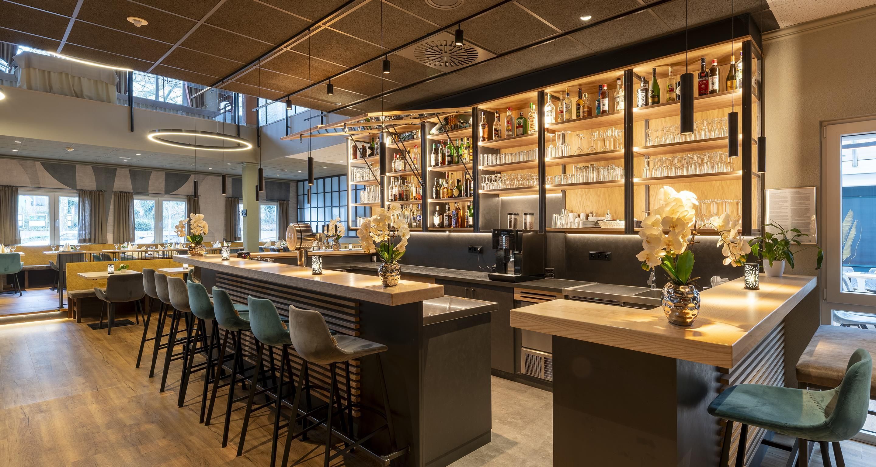 A modern bar area with a bar counter, seating, and a variety of bottles and glasses.