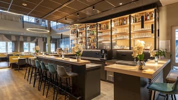 A modern bar area with a bar counter, seating, and a variety of bottles and glasses.