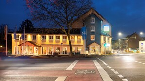 Un hôtel à plusieurs étages, avec une entrée au niveau du sol, une piste cyclable et un passage piéton.