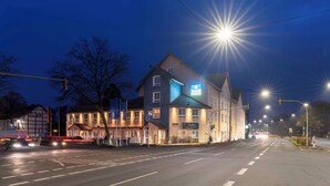 Un hotel a più piani con una segnaletica ben visibile, una strada illuminata e una disposizione stradale chiara.