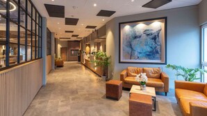 Una moderna hall d'albergo con scrivania della reception, area relax e un grande quadro astratto appeso alla parete.