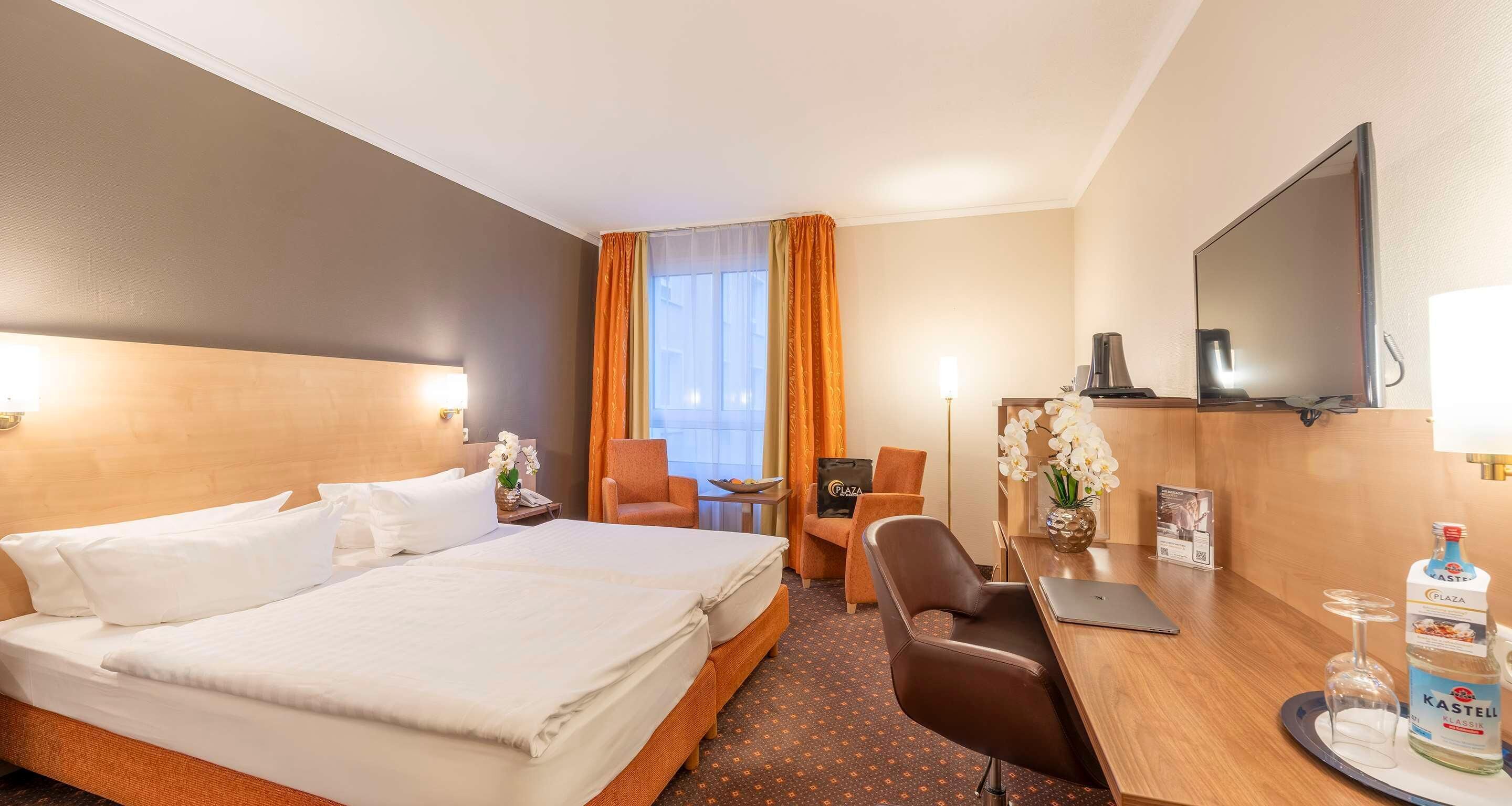 Une chambre d’hôtel avec un grand lit, un bureau avec une chaise, une télévision et un minibar.