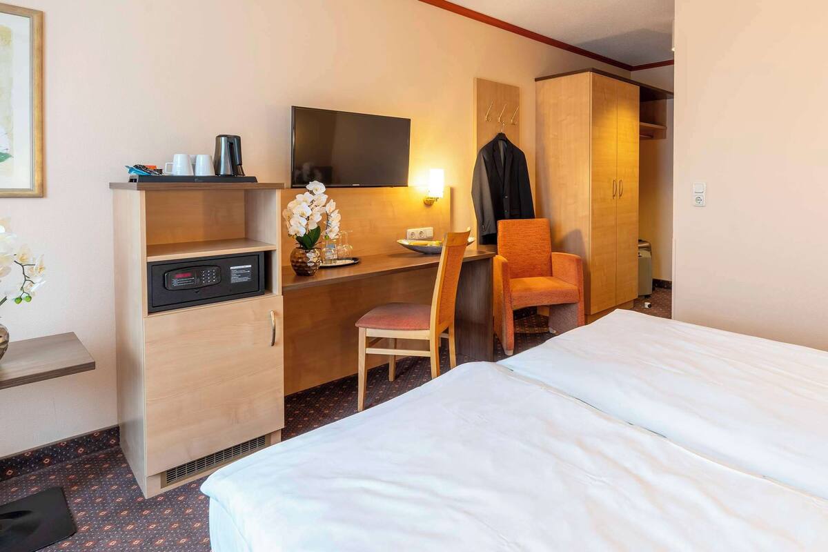 Een hotelkamer met een bed, een bureau met stoel, een televisie en een kledingkast.