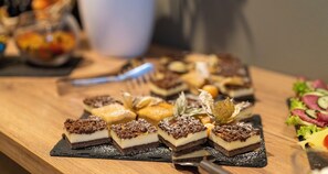 Een rijk gevulde dessertschotel met diverse desserts op een houten tafel.