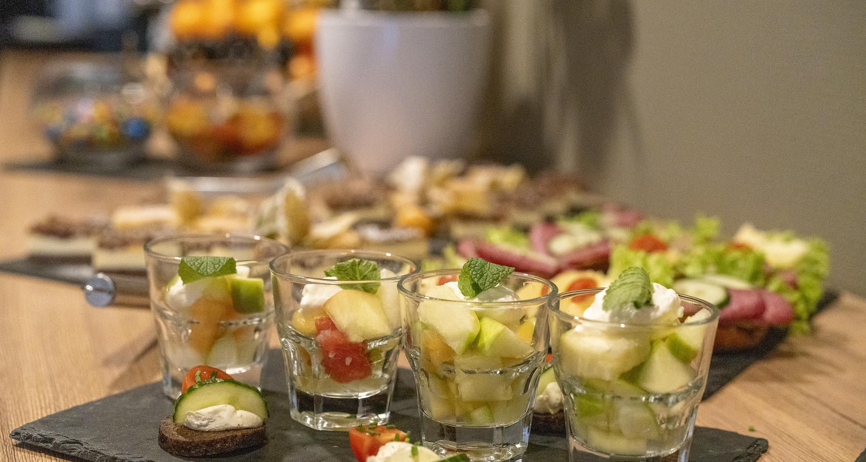 A table with various food items, including fruit and cheese, and a pitcher of a beverage.
